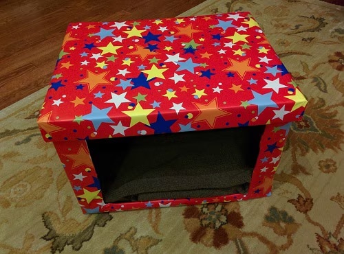 DIY Cardboard cat bed covered in red fabric with different colored stars.